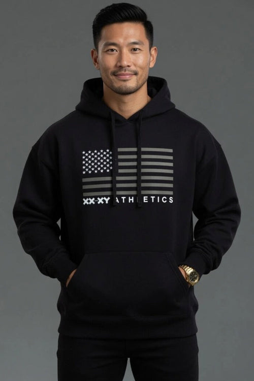 Man wearing a black hoodie with a flag design and 'XXXY Athletics' text on a gray background || Black