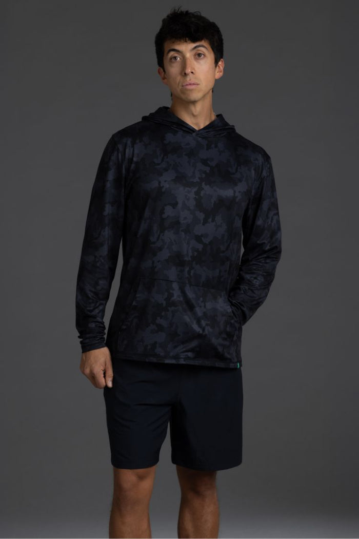 Person wearing a black camouflage hoodie and shorts on a gray  background || Black Camo