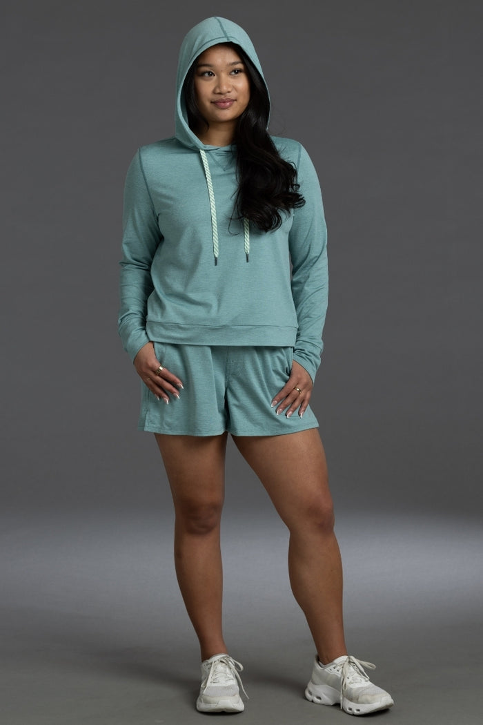 Woman wearing a teal hoodie and shorts set on a gray background || Underseas