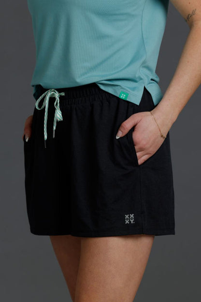 Person wearing a light blue shirt and black shorts on a dark background || Black